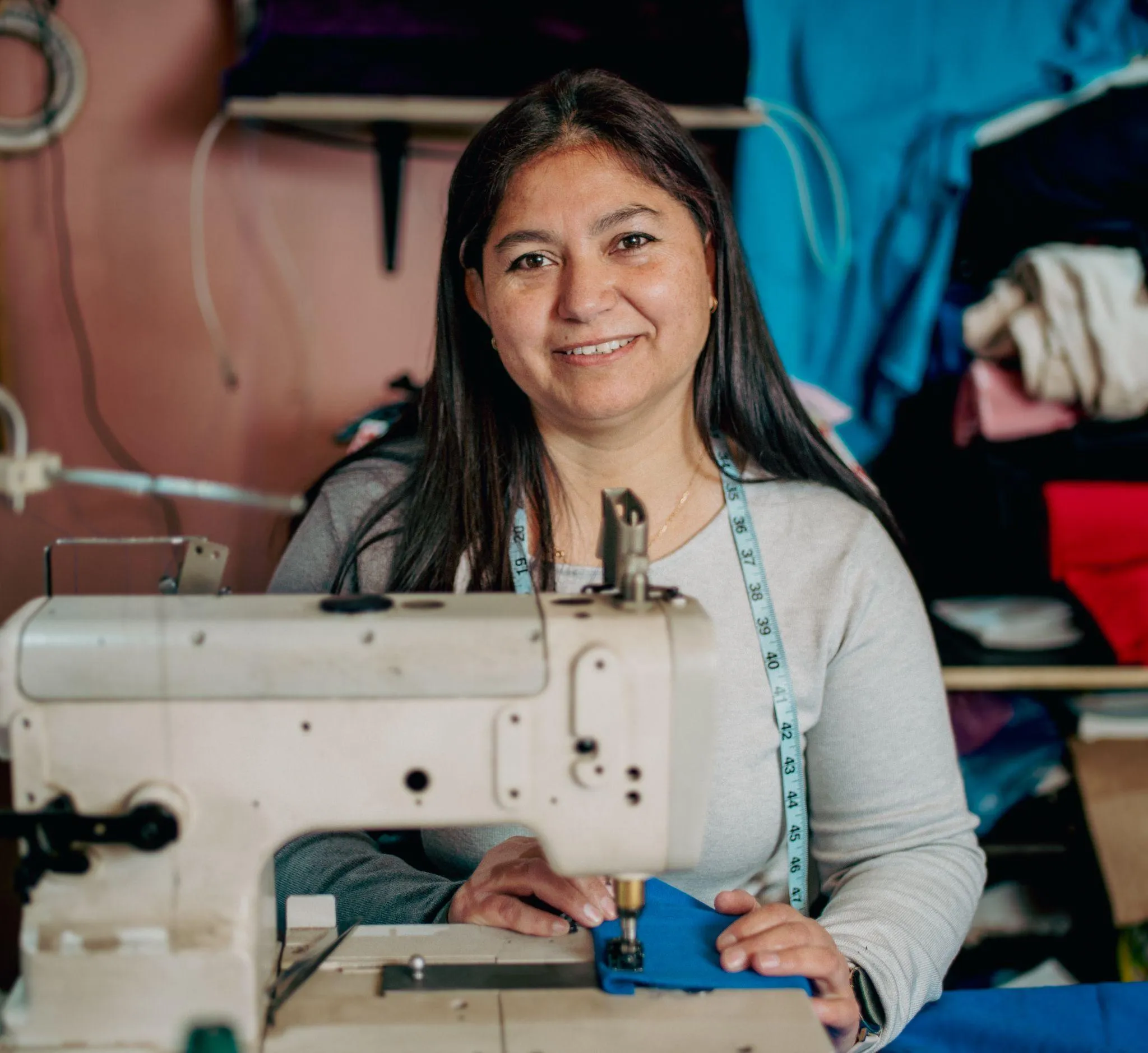 Emprendedora latinoamericana sonriendo en su taller de costura, ejemplo de las MiPymes que entrena PowerCamp